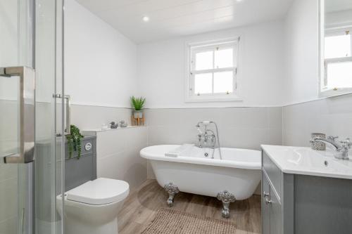 a bathroom with a tub and a toilet and a sink at Skye Sands - City Road Residence - Central St Andrews in St. Andrews
