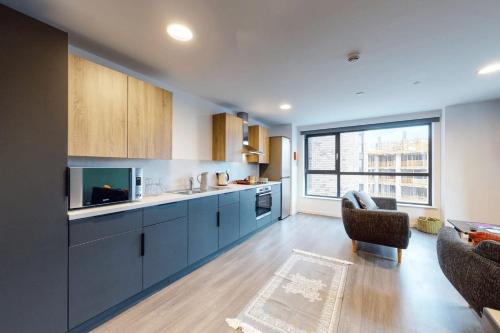 a kitchen with blue cabinets and a living room at Canvas Wembley in London in London