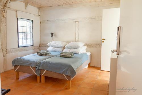 Nyord的住宿－Ragnhilds Gård, Hostel，一间卧室配有带白色床单和枕头的床。