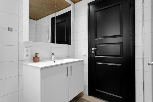 a bathroom with a sink and a black door at Luxury Country Cottage with 360° Mountain View in Brautarholt