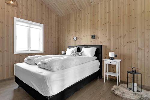 a bedroom with a large white bed and a window at Luxury Country Cottage with 360° Mountain View in Brautarholt