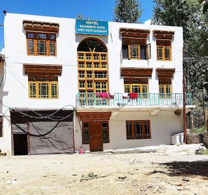 a white building with a balcony on top of it at Hotel Border View in Kargil