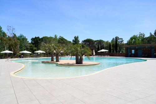 a large swimming pool with trees and umbrellas at Camping Campo dei Fiori in Vada