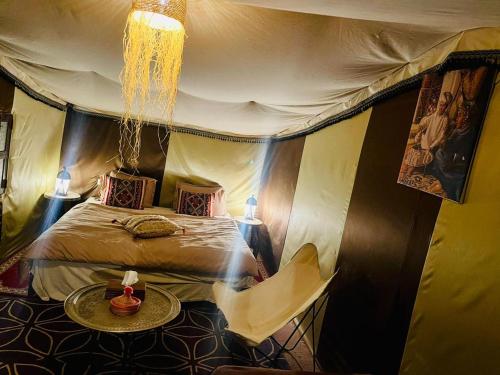 a room with a bed and a table in a tent at berber sahara in Zagora