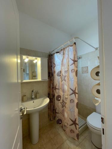 a bathroom with a sink and a toilet and a shower curtain at Villa Gelly's Studios in Aliki