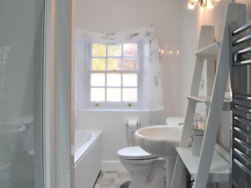 a white bathroom with a sink toilet and a window at Glebe Cottage in Urray