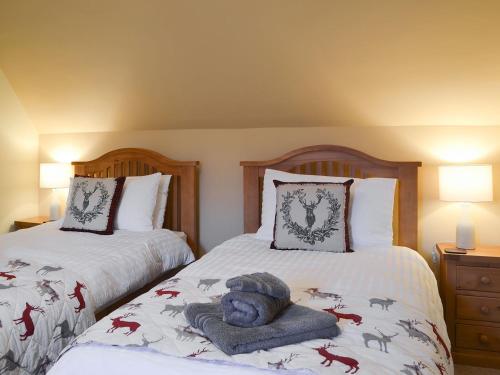 a bedroom with two beds with a teddy bear on it at Glebe Cottage in Urray