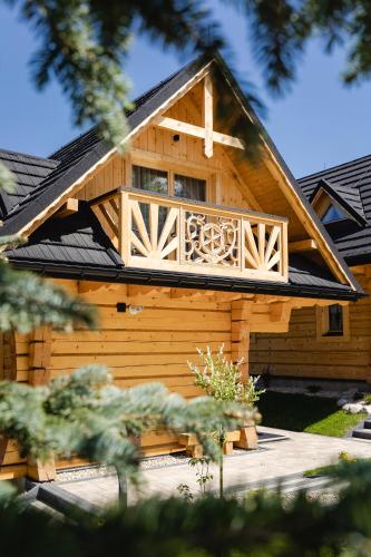 a log cabin with a balcony on top of it at Osada Chłabówka Zakopane & SPA in Zakopane