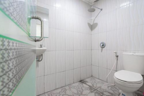 biała łazienka z toaletą i prysznicem w obiekcie RedDoorz Syariah at Cigadung Raya Street w mieście Bandung