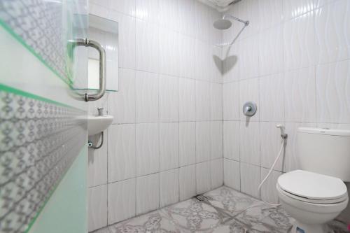 a white bathroom with a toilet and a shower at RedDoorz Syariah at Cigadung Raya Street in Bandung