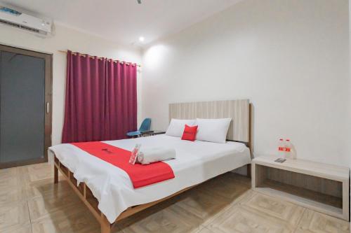a bedroom with a large bed with a red blanket at RedDoorz Syariah at Cigadung Raya Street in Bandung