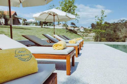 a row of chaise lounge chairs with umbrellas at Oliveiras Village — Agroturismo in Amarante