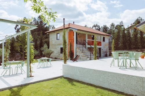 a patio with tables and chairs in front of a house at Oliveiras Village — Agroturismo in Amarante