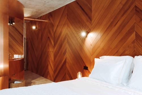a bedroom with a wooden wall and a bed with white pillows at Oliveiras Village — Agroturismo in Amarante