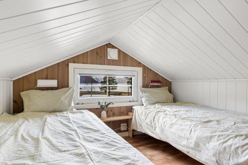 two beds in a attic bedroom with a window at Mikkelparken Ferietun in Kinsarvik