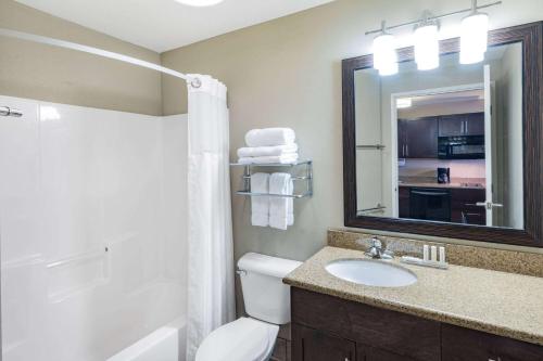 a bathroom with a toilet and a sink and a mirror at Hawthorn Suites by Wyndham Williston in Williston