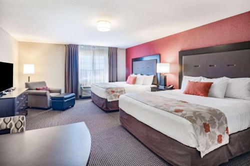 a hotel room with two beds and a television at Hawthorn Suites by Wyndham Williston in Williston