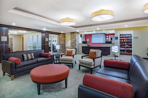 a waiting room with couches and chairs and a tv at Hawthorn Suites by Wyndham Williston in Williston