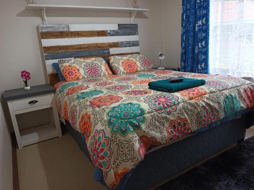 uma cama com um edredão colorido e uma mesa de cabeceira em Lincoln Place, Farningham Ridge em Pinetown