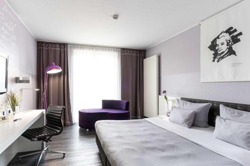 ヴォルフェンビュッテルにあるelaya hotel wolfenbuettel ehemals Rilano 24 7 Hotel Wolfenbüttelのベッド、デスク、椅子が備わるホテルルームです。