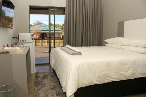a bedroom with a white bed and a window at Alu Boutique Hotel and Conference in Roodepoort