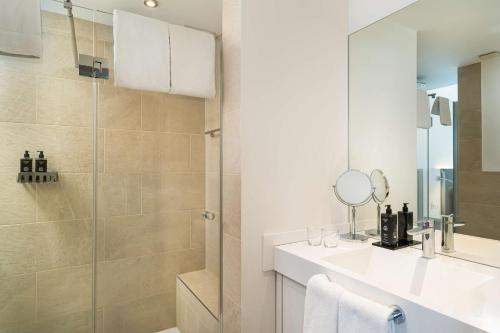 ein Bad mit einer Dusche, einem Waschbecken und einem Spiegel in der Unterkunft elaya hotel kleve in Kleve