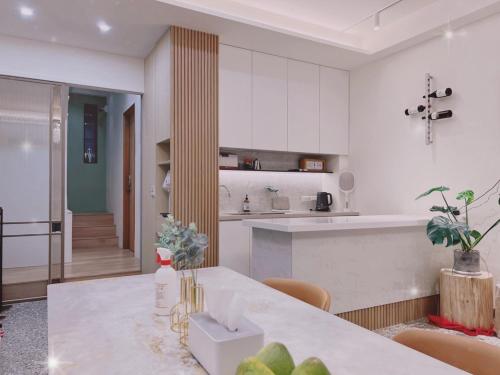 a white kitchen with a table and a counter at HoME-Easyhouse-III in Tainan