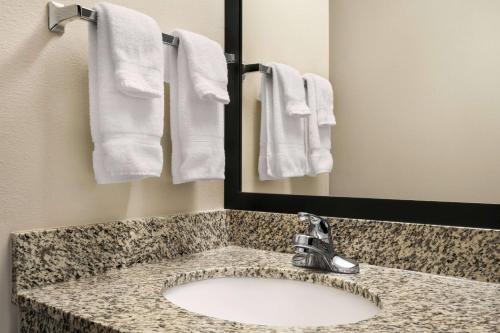 a bathroom with a sink and a mirror and towels at Baymont by Wyndham Rawlins in Rawlins