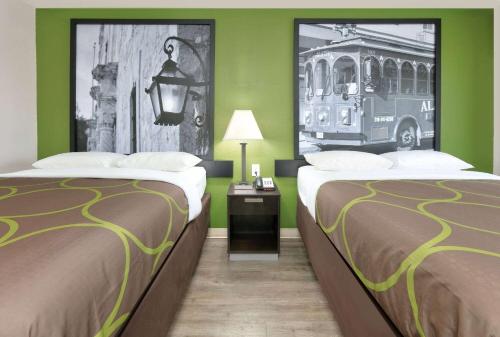a hotel room with two beds and a bus on the wall at Super 8 by Wyndham Palestine TX in Palestine
