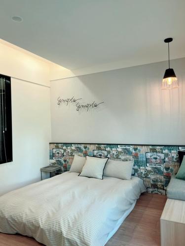a bedroom with a white bed with a sign on the wall at HoME-Easyhouse-III in Tainan