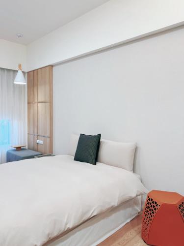 a bedroom with a white bed and a red stool at HoME-Easyhouse-III in Tainan
