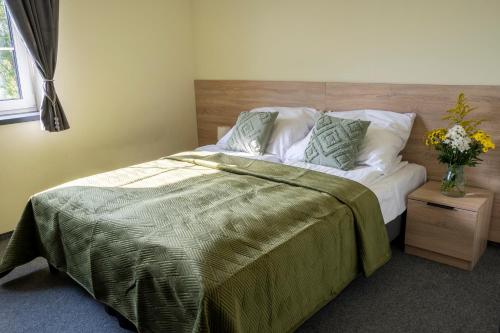um quarto com uma cama com um cobertor verde e um vaso de flores em Przy Skarpie Rozbark em Bytom
