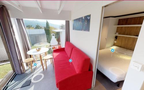 a room with a red chair and a bed and a table at Bungalows Portuondo parking gratuito in Mundaka