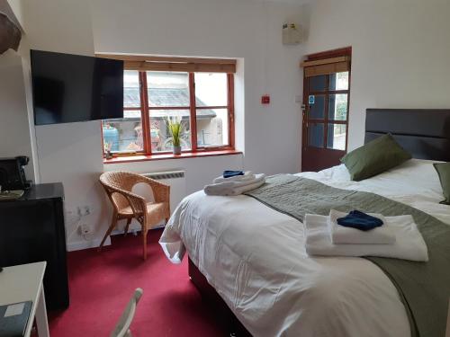 a bedroom with a bed and a chair and a television at The Ivy Barn Holbeton in Plymouth