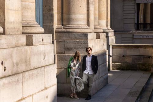 a man and a woman standing next to a building at Hotel Louvre Montana in Paris