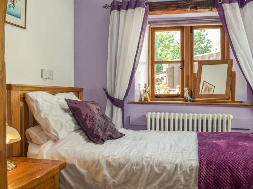 a bedroom with purple walls and a bed with a window at Swallow Barn in Haverfordwest