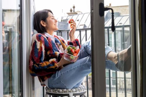 a woman sitting on a window sill eating food at Hotel Louvre Montana in Paris