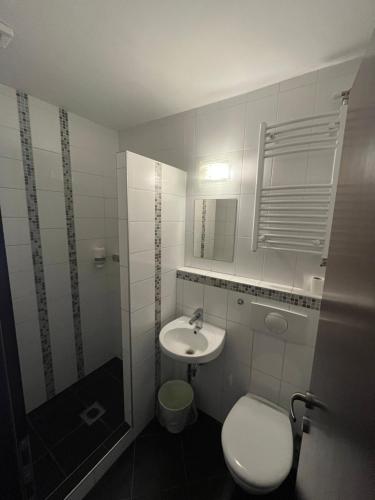 a white bathroom with a sink and a toilet at Centrál Borház - Étterem és Panzió in Érd