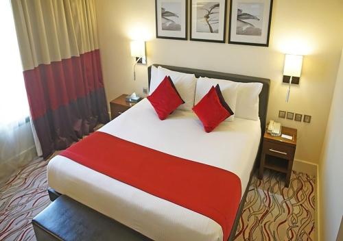 a hotel room with a large bed with red pillows at Novotel Suites Riyadh Olaya in Riyadh