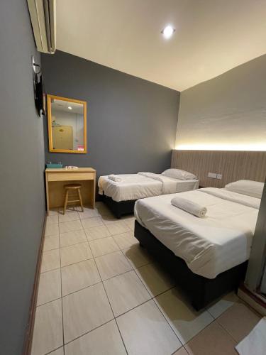 a hotel room with two beds and a mirror at Fresh Hotel Falim in Ipoh