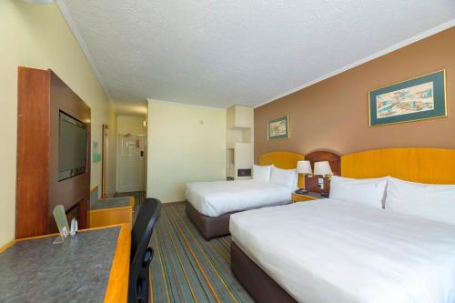 a hotel room with two beds and a desk at Holiday Inn - Bulawayo by IHG in Bulawayo