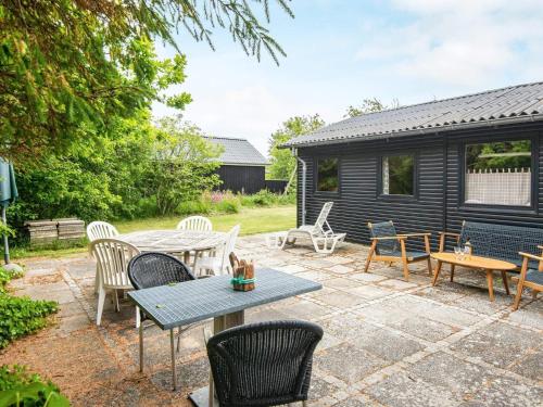 um pátio com uma mesa e cadeiras e um barracão em 6 person holiday home in Ulfborg em Ulfborg