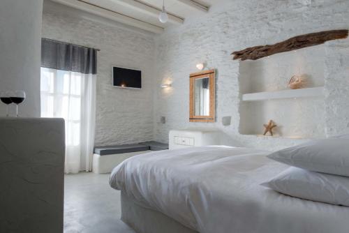 a white bedroom with a large bed and a window at Yialos Ios Hotel in Ios Chora