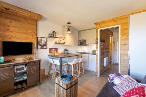 a kitchen and living room with a table and chairs at Résidence Le Necou - Les Ménuires in Les Menuires