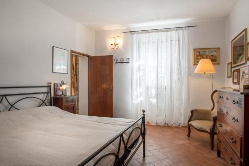 um quarto com uma cama, uma cadeira e uma janela em Residenza Porta all'Arco em Volterra