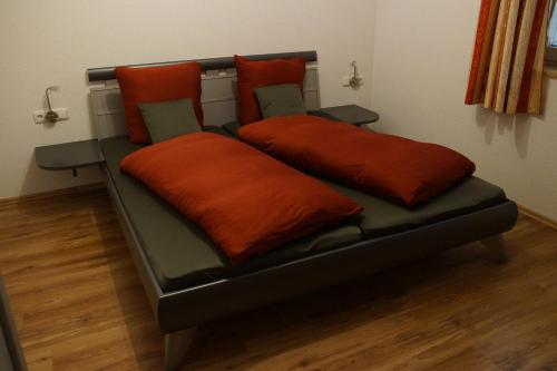 a bed with two orange pillows on top of it at Apart Midi in See