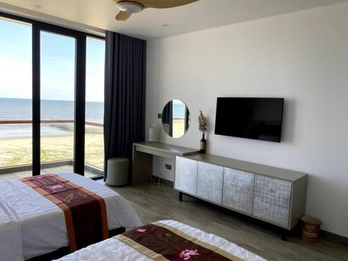 1 dormitorio con TV, cama y espejo en Biệt thự nghỉ dưỡng mặt biển, cao cấp và riêng tư en Ba Ria