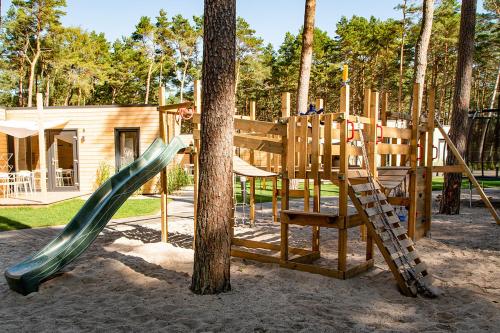 einen Spielplatz mit Rutsche und Baum in der Unterkunft Seaside Harmony in Pogorzelica