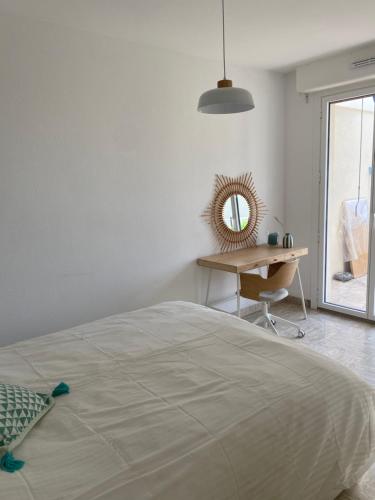 - une chambre avec un lit, un bureau et un miroir dans l'établissement Terrasse plein Sud - chaleureux en centre ville, à Hyères