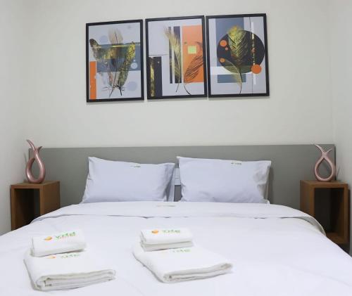 a bedroom with a white bed with four pictures on the wall at VR2 Hotel in Lençóis Paulista